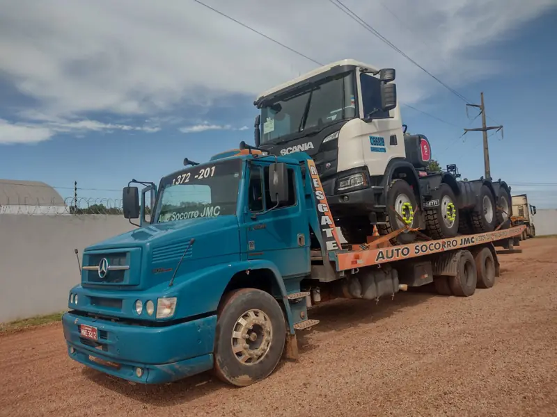 Flatbed tow truck carrying a truck cab